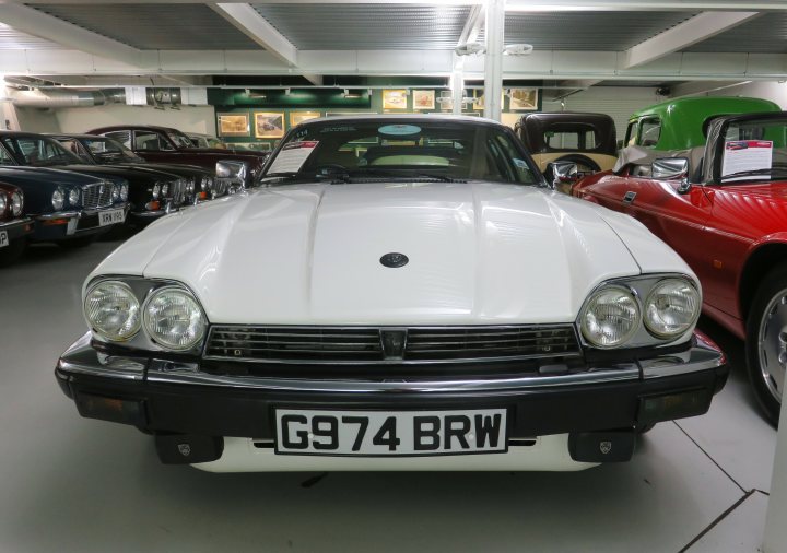 Pistonheads - The image depicts a vintage car, specifically a white Triumph Dolomite Sprint, displayed inside a building that appears to be a showroom or exhibition space. There are other cars visible in the background, suggesting this might be part of a larger collection or event. The focus is on the classic sports car, which is positioned centrally and occupies a significant portion of the image. The lighting and composition suggest that this photo was taken to highlight the vehicle's features and design.