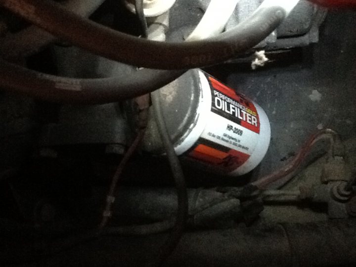 Ford Crossflow Oil Filter ? Not - Page 1 - Classics - PistonHeads - The image is taken up close and focuses primarily on motor system components and a cylindrical container with the word "OIL" visible in black lettering on a red background. The canister looks new and sealed, and there's a usage code or model number written below the word "OIL." The overall ambiance of the image is dark and metallic, suggesting that the photo might have been taken within an industrial or mechanical setting such as the underside of a vehicle. The composition of the image implies an inspection, service, or maintenance activity is taking place.