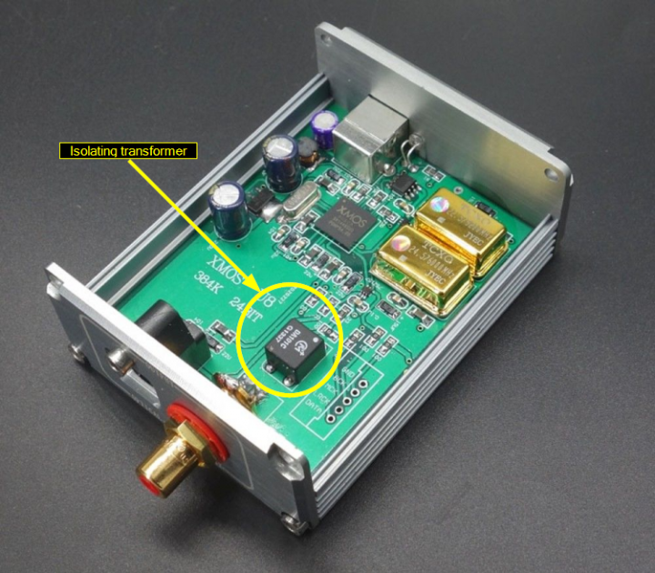 More 'Audiophile' bullsh*t. - Page 77 - Home Cinema & Hi-Fi - PistonHeads - The image displays a piece of electronic equipment, specifically a circuit board mounted in a metal casing with a green top. The circuit board contains various components such as a microchip, connectors, and resistors. A small gold-colored transformer is visible on the board, attached to one end of it. To the right, there's an external antenna, and a red LED light is lit on the top of the board. The image is taken from a side angle, focusing on the circuit board with its components highlighted in text. There's no immediate context provided, leaving the exact purpose or function of this device unclear.