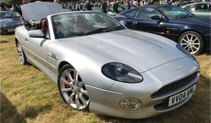 Lets see a picture of your classic(s) - Page 417 - Classic Cars and Yesterday's Heroes - PistonHeads - The image shows a silver convertible sports car parked on grass. There are other cars and people in the background, suggesting this might be at an outdoor event or show. The vehicle has its top down, revealing a convertible roof structure. The design of the car is sleek and modern, with alloy wheels visible.