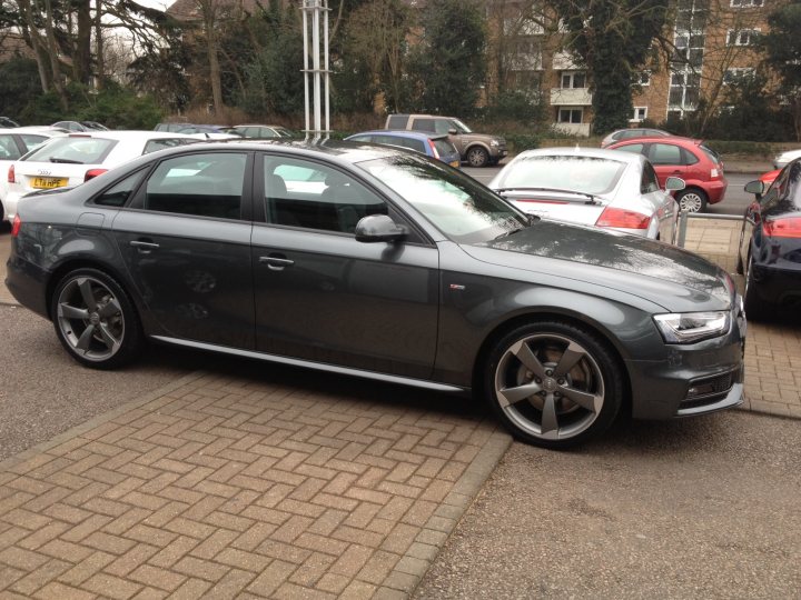 A car is parked in front of a parking meter - Pistonheads - The image depicts an asphalt parking lot with multiple cars parked side by side on a clear day. The focus of the image is a silver Audi coupe that is parked in the foreground. The car has a noticeable shine to it, and the reflective surface of the car indicates that it might be relatively new. There are other cars parked in the background, including a red car to the right of the Audi. The ground is composed of a brick-like pattern, and it seems like it's a relatively orderly and clean parking area. No people are visible in the image, emphasizing that the focus is on the cars.