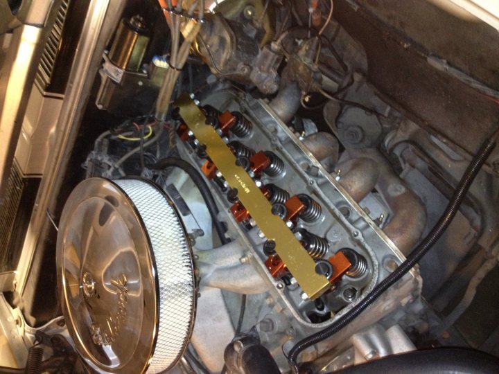 A close up of a motorcycle parked in a garage - Pistonheads - The image provides a close-up view of an engine area beneath a vehicle's floor, lying on a tilted floor. The engine appears complex with visible metal, tubing, hoses, and multiple colored wires. There are various mechanical components, and a shiny muffler with the word "Magnaflow" is suspended next to the engine. The view offers a sense of the engine's robustness and the intricacies of its design and construction. The photo gives an overall impression of a well-maintained and tidy automotive setting.