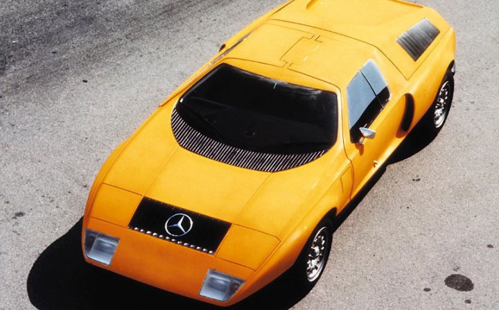 Pistonheads Evades Crosschannel Merc Crooks - The image showcases a striking yellow 1980s Mercedes vehicle, most likely an AMG model, as indicated by the badges on its hood. The car is positioned at an angle, highlighting its sleek design and glossy paint. Its rectangular shape and the spoiler on the roof add to its sporty aesthetic. The background is nondescript, allowing the viewer to focus solely on the car.