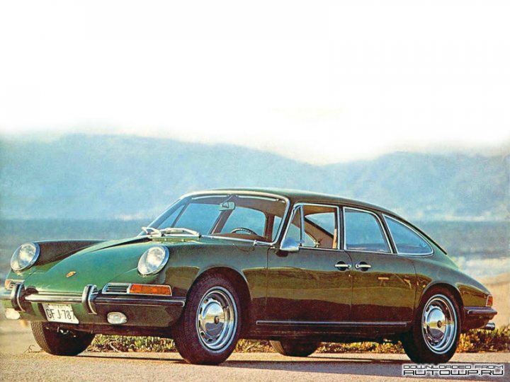 A classic car with a surfboard on top of it - Pistonheads - The image is of a vintage sports car parked on a road, featuring a vibrant green color and a classic wedge shape typical of certain models from the 1960s and 1970s. The vehicle has two doors, dual round headlights, and a sunroof. Its wheels and trim are also painted in green, matching the car's body. The car's style suggests it could be a Porsche, but the specific model is not identifiable from the image provided. The background reveals a scenic road with an open sky, mountains in the distance, and a clear sky. There is a watermark in the lower corner which reads "Rute66 Origins."