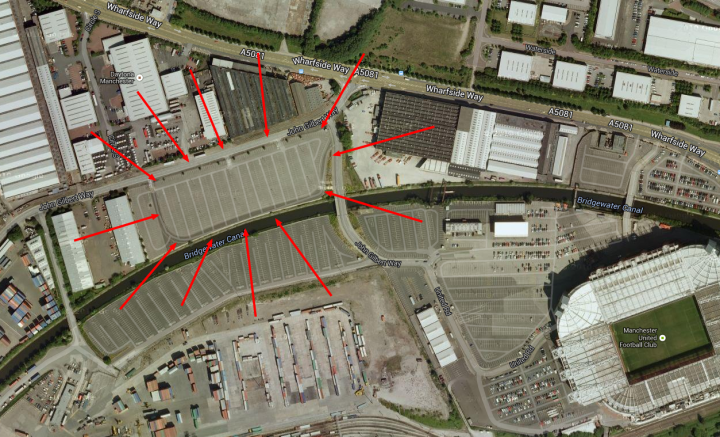 A train station with a train on the tracks - Pistonheads - The image presents an aerial satellite view of a large, rectangular parking lot surrounded by buildings. The red circles drawn on the satellite image serve to point out the layout and size of the parking lot. To the right of the parking lot, there is a prominent athletic stadium. Surrounding the stadium, there's a complex with multiple structures and what appears to be a courtyard. The entire scene suggests a central location within a city or urban area.