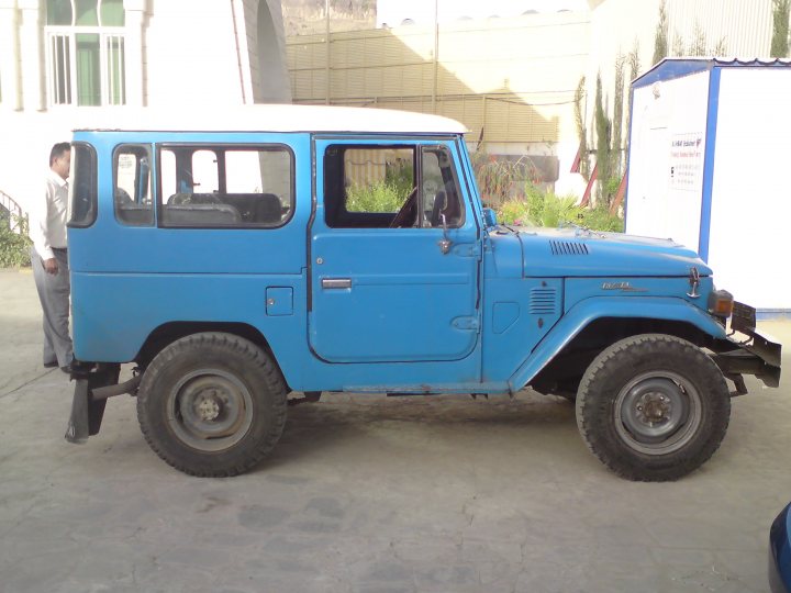 Pistonheads - This image features a vintage blue jeep parked on what appears to be a concrete surface. The vehicle's distinctive color and boxy design suggest it's an older model, possibly a Land Rover given its sturdy appearance. In the background, part of a building can be seen, along with a person and a plant. The jeep, with its classic functionality, seems to stand upright even against the passage of time, adding a touch of nostalgia to the scene. Despite the absence of the jeep's hood, it retains a certain rugged charm.