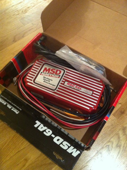 A suitcase with a bag of luggage on it - Pistonheads - The image shows a red and black MSD Motion Sensing Development Board box partially opened on a wooden floor. Inside the box, you can see the board itself, along with a coil of wires and a zippered plastic bag. The board has a red and black case with a label that reads "FIRESONIC." The brand name "MSD" is visible on the board and the box.