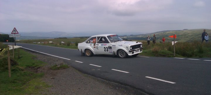 A white truck driving down a road next to a forest - Pistonheads