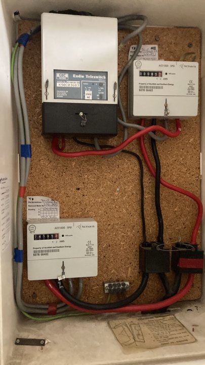 Help with electricity meter please - Page 1 - Homes, Gardens and DIY - PistonHeads UK - This image shows an electrical panel with various components installed. On the left side of the panel, there is a white box with several controls and indicators on it. Below this, a series of red cables are connected to multiple terminals. There's also a fuse or breaker in the center, which is part of the panel's protective system. The panel appears to be properly secured and organized, with all components in place. It looks like a standard electrical box that one would find in a house or small building.