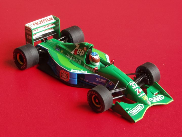 Collection Pistonheads - The image shows a die-cast model of a race car placed on a red background. The car is green with blue and white details, and it's adorned with the number 7. A logo on the side of the car reads "Brookfield." The wheels are black with silver accents, contributing to the realistic look of the model. The overall image is a close-up of the car, capturing its intricate details and vibrant colors.