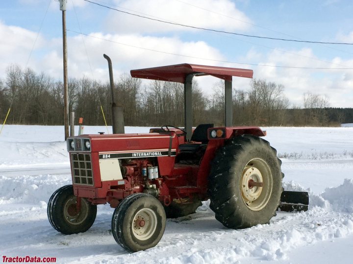 Car model number game - Page 41 - General Gassing - PistonHeads - The image features a vibrant red John Deere tractor parked on a snow-covered field. The tractor is facing the camera, with its hood slightly open, revealing the engine beneath. The sky above is cloudy, suggesting it might be winter or early spring. There's no sign of the tractor operator, but the presence of tire tracks in the snow indicates recent activity around the vehicle. In the background, there's a glimpse of a rural landscape with trees and a fence line, reinforcing the sense of a farm setting.