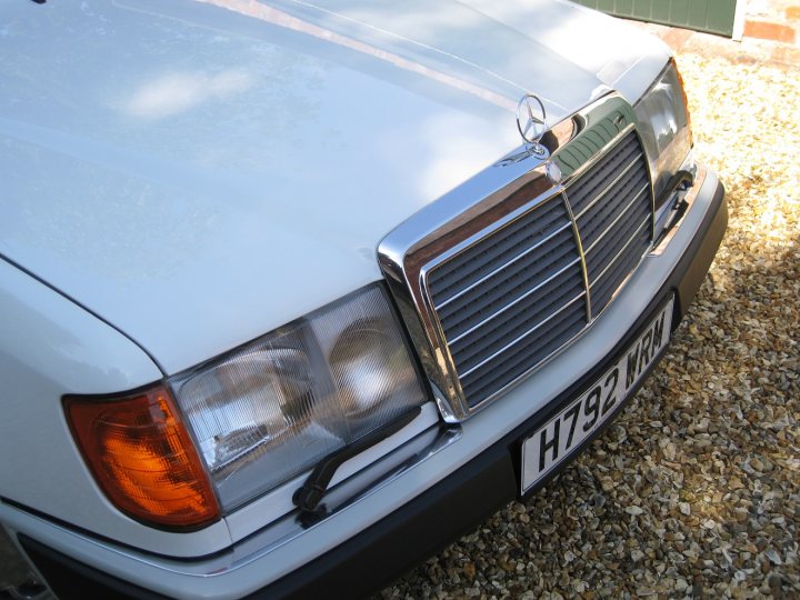 Best smoker barges 1-5 large [vol8] - Page 431 - General Gassing - PistonHeads - The image shows the front of a white vehicle, likely a classic or luxury model, based on the distinctive grille and emblem. This emblem is a Mercedes-Benz logo, indicating the type of vehicle. The grille itself appears to be chrome-colored with a distinctive radiator design. The vehicle is parked on gravel, suggesting an outdoor setting. The sunlight casts a soft glow on the car's surface, highlighting the shine of its bodywork.