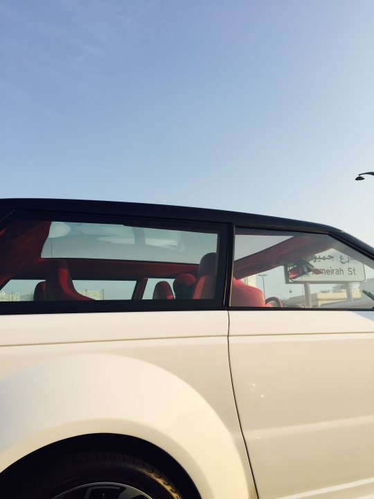 Middle East spotted thread - Page 76 - Middle East - PistonHeads - The image captures the modern and sleek design of a white car, seen through the perspective of a side window. The car's black ceiling adds a contrast to the white body, giving it an elegant appearance. The car appears to be stationary outdoors with the sky visible in the background. There are no people visible in the window reflection. The car takes up most of the frame, emphasizing its design and color.