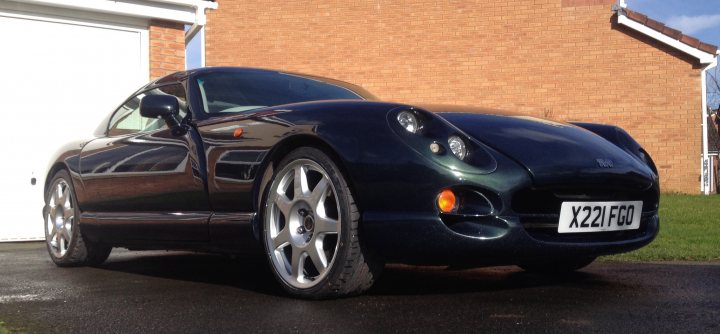 RL7s, 18"x9", Hens teeth? - Page 1 - General TVR Stuff & Gossip - PistonHeads - The image features a black sports car prominently positioned in the foreground, taking up a significant portion of the frame from left to right, highlighting its sleek design and finished surface. It's parked on a driveway near a brick building, with the license plate reading "XZ21 FOG," suggesting it's late afternoon, as indicated by the clear sky in the background. The rear end of the car is visible, showcasing its distinctive taillights and the logo on the trunk.