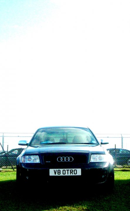 Mrc Pistonheads Dyno - The image features a sleek black Audi car parked on a lush green lawn. The vehicle is turned slightly to the left, giving a clear view of the car's front and side. The Audi logo is prominently displayed on the front grille. The car is positioned close to a fence, which separates the lawn from a field. The environment seems to be outdoors on a bright day. The license plate on the car reads "V8 OTRO".