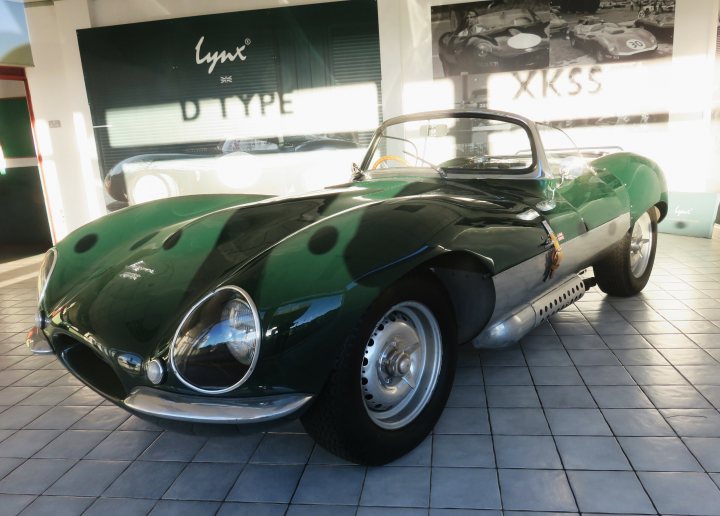 Pistonheads - This image captures a moment in a showroom or dealership, where a vintage green and white sports car is on display. The car's classic design, featuring round headlights and a polished exterior, suggests it's from an earlier era of automobile history. It's parked inside a building with a sign that reads "XXX," possibly indicating the brand or model of the vehicle. The background also shows other cars in the room, suggesting that this could be a specialized dealership or showroom dedicated to classic and sports vehicles.