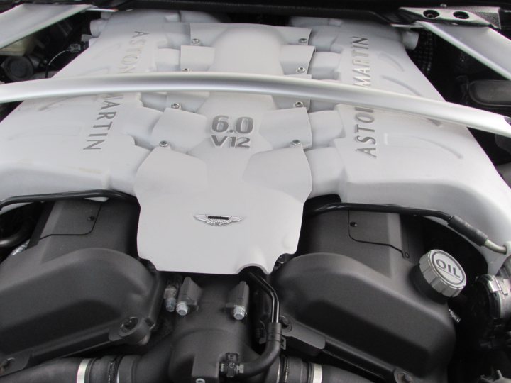 Supercars spotted, some rarities (vol 6) - Page 469 - General Gassing - PistonHeads - The image shows a close-up view of the engine bay of a Mercedes-Benz car. Visible is a white plastic cover with the model number "60 V12" indicated twice. The engine features the Mercedes logo with the lion and the star symbol. There are meticulously arranged air conditioning vents in the foreground. The overall image is a photograph with a focus on the engine's components and identification.