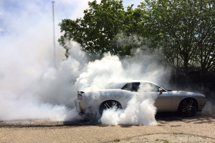 A small boat in a body of water - Pistonheads - This image captures a dynamic scene of a white car, positioned at a diagonal angle to the frame, releasing a substantial amount of white smoke from its tires. The vehicle is imbued with an air of speed or power, as the smoke billowing out from the tires suggests high speeds or aggressive driving. The backdrop features clear blue skies, adding to the outdoorsy and open feeling of the image. There are also a few trees visible, enriching the natural elements within the scene. The entire image has a vibrant and energetic atmosphere, enhanced by the play of light and shadow.