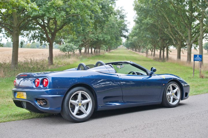 What to Buy -F355-360-F430??? - Page 6 - Supercar General - PistonHeads - The image captures a luxurious convertible car, painted in a vibrant shade of blue, parked on the side of a tree-lined road. The car is positioned in such a way that it's facing away from the viewer, showcasing its sleek design and shiny details. The surrounding landscape is peaceful and serene, with grassy fields stretching out into the distance. Amidst the greenery, a few signposts can be seen, adding a touch of civilization to the otherwise natural setting. The perspective of the photo suggests that the viewer is standing at an angle, slightly behind the car, providing a comprehensive view of the picture-perfect scene.