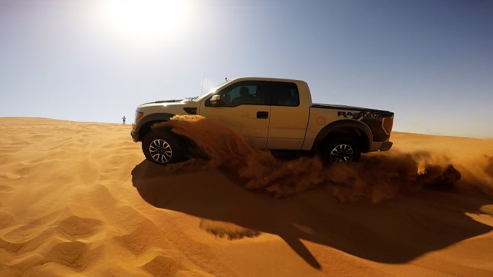 TVRs in Dubai  - Page 1 - Middle East - PistonHeads - The image shows a white pickup truck driving through a sandy landscape with ripples and large dunes visible. The vehicle appears to be in motion, with a large plume of sand being kicked up behind it. The truck has a robust, off-road design, and the style of the image is a dynamic action shot, capturing the moment of the truck's journey in a desert environment.