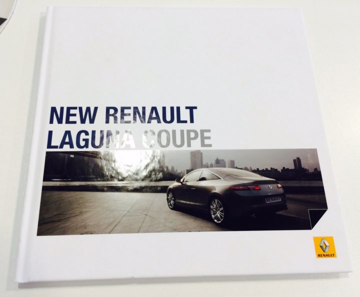 Laguna Coupe 3.0 dci - bad idea? - Page 1 - French Bred - PistonHeads - The image is of a book titled "New Renault Laguna Coupe." The cover features a photograph of a luxury sedan parked on a concrete surface with a city skyline in the background. The top right corner of the cover displays a logo which appears to be a stylized letter 'C.' The design of the book suggests a premium or high-end topic, possibly a sales brochure or a review of the car.