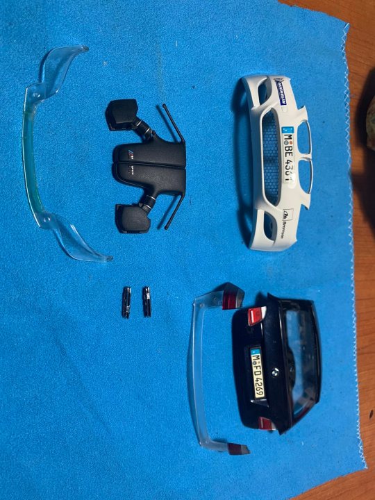 A group of different types of remote controls - The image presents a collection of car models arranged on a blue surface. There are two cars, one larger and one smaller, with visible bodywork that suggests they might be model or toy versions rather than functional vehicles.