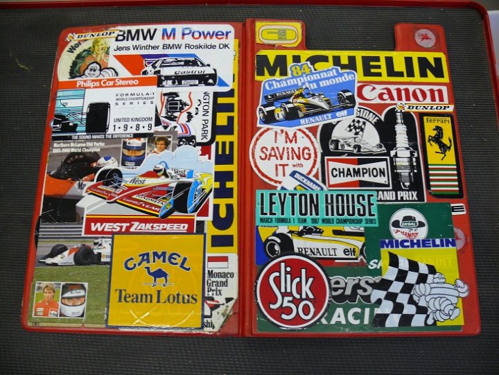 Show Us Your Stickers! - Page 1 - Formula 1 - PistonHeads - The image presents a collection of stickers adhered to a surface. The stickers feature various car brands including BMW, Mercedes, and Michelin, with some car racing-related imagery as well. The stickers are vibrant and colorful, emphasizing the automotive domain, and they are arranged in a bunch without any order. The style of the image is a close-up photograph capturing the details of the stickers.