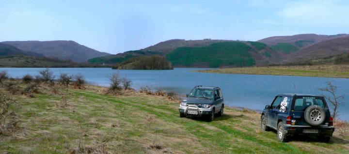 background car pics :) - Page 15 - Readers' Cars - PistonHeads - The image portrays a serene outdoor scene with two SUVs parked on a grassy field. The SUVs, one in the foreground and the other slightly behind it, are facing each other as if they are ready to embark on drives around the picturesque location. The field is situated on a hillside, offering a panoramic view of a lake nestled in the distance. Mountains loom in the background, suggesting a high altitude or remote location. The calm blue water of the lake contrasts with the overcast sky, suggesting either early or late hours. The overall picture is one of peace and tranquility in nature.