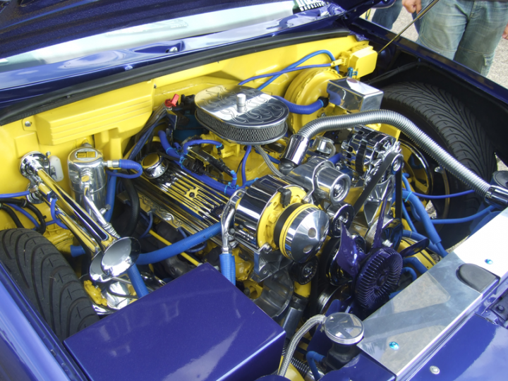 Truck Chevy Pistonheads - The image captures the intricate and vibrant undercarriage of a blue and yellow car that is laid out in a way that the engine is visible. The color scheme of the car and its components suggests a high level of engineering or customization. The engine is a powerful V8 unit featuring four distinct silver cylinders, and is accentuated with gold accents. There are various pipes, hoses, and wiring that create a complex network under the hood, indicating a well-maintained and possibly performance-modified vehicle.