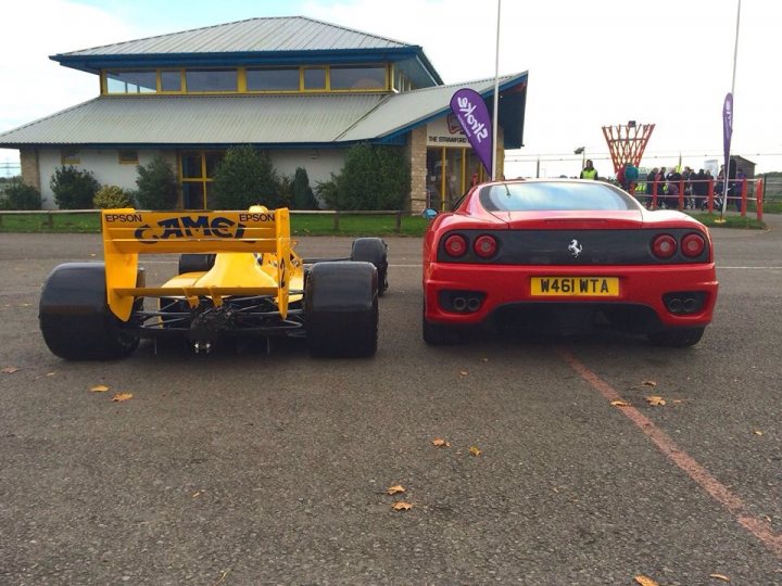 A yellow and blue truck is parked in a lot - Pistonheads - This image captures a scene at a carnival or outdoor event area with tents set up. There are two sports cars parked side by side, drawing attention to their vibrant colors and sleek designs. The yellow racing car, with its striking design and the word "CAMPION" written on the back wing, sits next to a red sports car with the number "N45 W0G" displayed on its license plate area. The scene suggests a motorsport event or a group of enthusiasts gathered to show off their exotic vehicles.