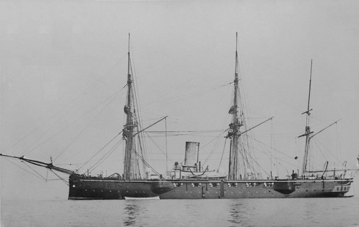 Apparently Pistonheads Battleships - The image is a black and white photograph featuring two ships on water. The foreground shows a large sailing ship, capturing the red mizzen topsail, the white foremast topsail, and the white smokestack. The background features another, smaller ship. Both ships maintain their profile toward the image, and both show multiple masts. They appear to be in the distance, as suggested by their smaller size compared to the main ship. The blurred figure in the background may be a crew member or sail. The water surface shows ripples, suggesting that the ships are cruising. Despite the age of the photo, the level of detail in the rigging and the shape of the vessels demonstrates the artist's skill and time.