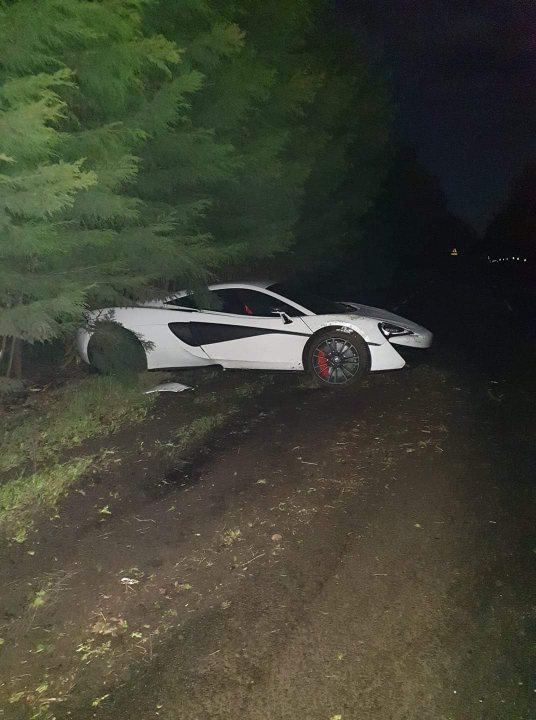 Anyone missing a mclaren.... - Page 1 - McLaren - PistonHeads - The image shows a scene at night featuring an abandoned sports car. The car, a white Audi R8 with red detailing and black tires, is parked on the side of a dirt road next to a patch of grass and trees. There's no visible damage to the car or any signs of distress in its surroundings. The car seems to be in good condition. The road appears to be unpaved, suggesting a rural or semi-rural setting. The nighttime scene is devoid of people, emphasizing the isolation of the car and the area around it.