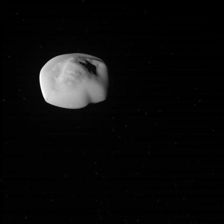 Saturn images - Cassini - Page 3 - Science! - PistonHeads - The image shows a white, cloud-like object suspended against a black background, which suggests it is set in the night sky. The object appears to have a distinct shape, resembling a crescent or an elongated oval. Its positioning and size indicate it is further away from the viewer. The contrast between the white object and the black background emphasizes the object's form and creates a sense of depth.