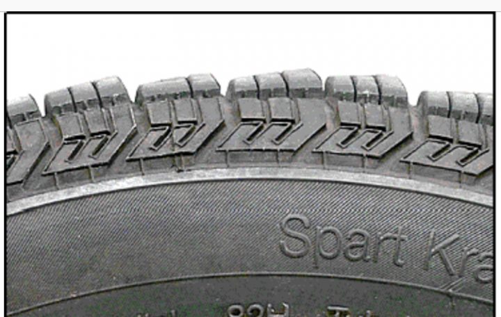 Droning tyre noise - possible cause? - Page 1 - General Gassing - PistonHeads - The image shows a side view of a cylindrical tire, which appears to be for a vehicle. It has an inscription on it reading "SPART KRA". The tire has visible treads, with numbers: 91, 99, and 00. The design of the tire is reminiscent of a traditional uneven road. The photograph has a washed-out look with parts of the tire appearing gray and other parts black, which gives it a vintage appearance.