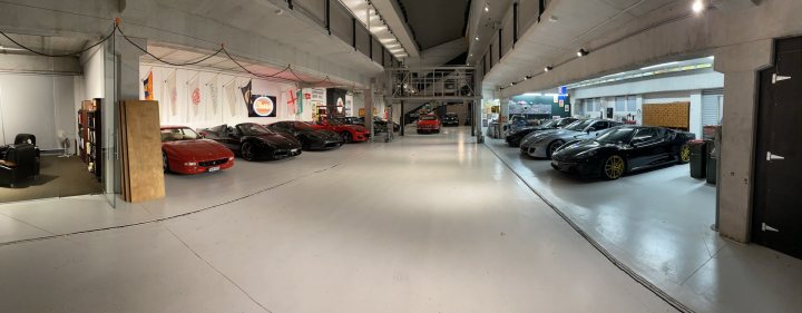 Who has the best Garage on Pistonheads???? - Page 302 - General Gassing - PistonHeads - The image shows a spacious and well-lit underground garage filled with various types of vehicles. There are numerous cars parked in rows, each one distinct in design and color. Some cars are positioned at the forefront of the frame while others can be seen further back. The ceiling is adorned with exposed ductwork, giving an industrial feel to the space. In the background, there's a visible structure resembling a stage or set-up area, suggesting that this garage might also serve as an event venue.