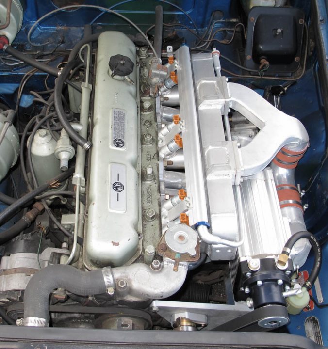 Pistonheads - The image shows the engine of a vehicle, a complex assembly of metal components and mechanical parts. There are various hoses and wires that suggest its power and functionality. The engine's number is visible, with "32" printed on one of the large components, which typically indicates the number of strokes and cylinders, a common method of engine identification. In the background, part of the vehicle's blue interior can be seen, indicating the viewer's perspective might be from inside the car.