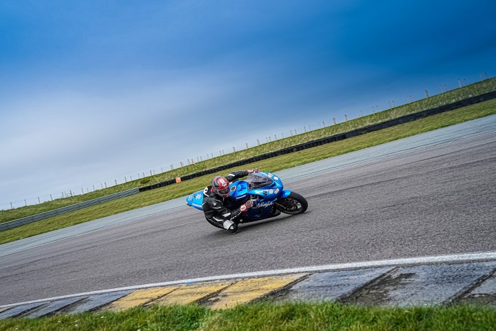 the bb trackday thread.   - Page 473 - Biker Banter - PistonHeads UK - The image captures a thrilling moment on a motorcycle race track. A rider in a blue suit is astride a vibrant blue motorcycle, leaning into a curve with skill and precision. The backdrop of the scene is filled with the blurred motion of other racers, suggesting a high-speed race in progress. The track itself appears to be located near a body of water, with a clear sky overhead, indicating good weather conditions for the event. There's no text visible in this image.