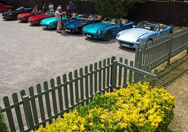 Impromptu meet up/drive out Cotswolds-ish - Page 4 - Chimaera - PistonHeads - In the image, we see a diverse collection of vintage cars parked in a driveway. The cars vary in color and model, but they all exude an air of nostalgia and elegance. They are all parked facing the same direction, as if marching in a neat row. 

A wooden fence stands guard in the foreground, serving as a rustic enclosure for a green manicured lawn and a bush with vibrant yellow flowers nearby. A path leading to a parking lot stretches out beyond the fence, inviting one to explore further. 

Despite the imposing nature of the cars, there is a sense of harmony and tranquility in the scene. The colors of the cars, the green of the lawn, and the yellow of the flowers create a soothing palette. The arrangement of the cars, fencing, and lawn suggest careful planning and attention to detail. The image conveys a sense of quiet pride in these vehicles, as well as the appreciation for vintage cars.