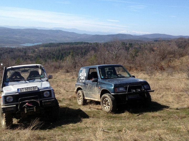 Bit of off-roading, and a bit of camping. - Page 1 - Off Road - PistonHeads - In the image, there are two Land Rovers parked on a grassy area. The vehicle in the foreground is covered in white snow, suggesting it has been stuck in the winter conditions of a nearby mountain. The Land Rover with the driver still in the vehicle makes these two vehicles the main focus of the image. The backdrop features rolling hills and mountains, creating a picturesque, yet rugged, setting. The snow-covered mountaintop adds a touch of tranquility to the scene, contrasting with the robust, adventurous spirit of the vehicles.