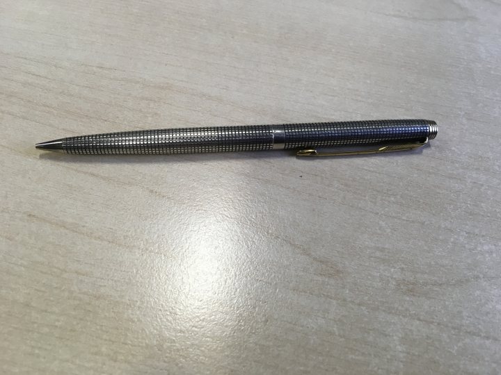 Do you use a fountain pen? - Page 149 - The Lounge - PistonHeads - This image shows a pen lying on a wooden surface. The pen appears to be made of metal with a silver or chrome finish. It has a transparent grip and is likely designed for ink.