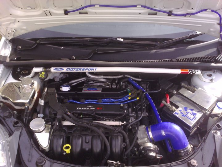 Fiesta Pistonheads - The image showcases the view of the engine bay of a car, with various components and wires visible. On the left side, there are parts that appear to be related to the car's suspension or emissions system, including what seems to be a sensor or possibly a high-performance battery with the label "DURATECH." On the right side, you can see the air intake system, which includes a blue-colored turbocharger or intake manifold. There are also two heat shields, one with the logo "Ford" and the other with the number "605," suggesting this is a Ford car engine. The overall scene suggests that this could be a Japanese import or a customized vehicle.