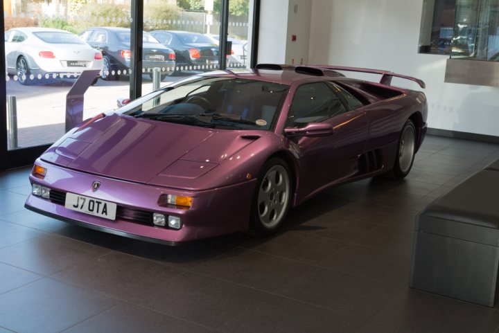 A car is parked on the side of the road - Pistonheads - The image features a purple, high-performance sports car on display inside a showroom. The car is a bright color and is positioned diagonally against a wall lined with polished tiles, showcasing its sleek design. The vehicle is adorned with a license plate that reads "J7OTA" and appears to be a Lamborghini, given its distinctive aesthetic. The setting suggests a professional environment where the car is being presented, likely attracting the attention of automotive enthusiasts.