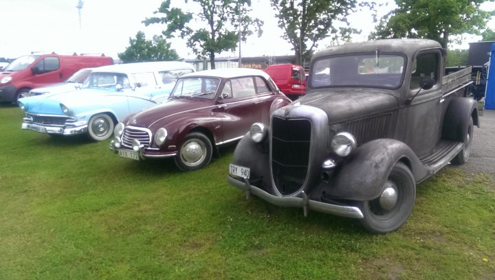 COOL CLASSIC CAR SPOTTERS POST!!! Vol 2 - Page 156 - Classic Cars and Yesterday's Heroes - PistonHeads - The image depicts a row of vintage cars parked on a grassy area. The cars range in color from antique white to a shiny maroon. They vary in style, suggesting different models and makes. The surrounding area includes vehicles parked further away, indicating a possible gathering or event. The overall atmosphere conveys a sense of nostalgia and appreciation for classic automobiles.