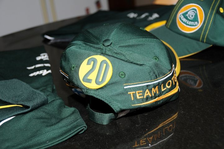 New Team Lotus Gear Turned up today!! - Page 1 - Caterham - PistonHeads - The image shows a collection of green hats arranged on a black surface. The hats feature a circular emblem on the front. The emblem is white with green and yellow text and stripes, reading "TEAM Lotus." On one of the hats, there's a larger number "20" emblazoned on the front. The style of the hats suggests a sporty or racing theme, possibly related to the Lotus F1 team given the team's association with the number 20.