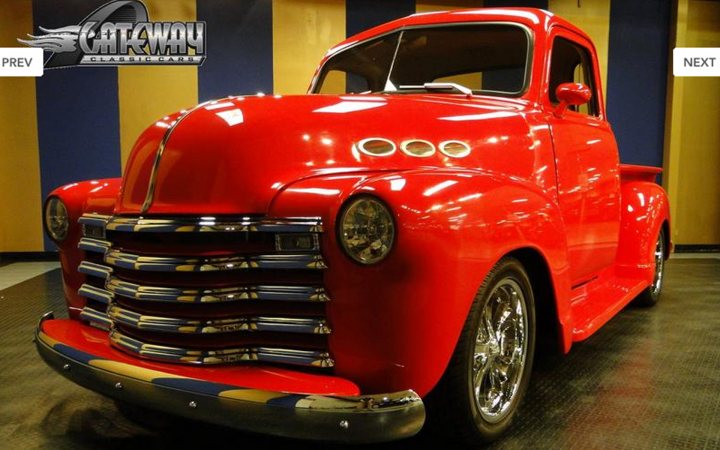 Pistonheads - This image features a vintage red pickup truck. It's a pre-model year vehicle, suggesting that the image could have been taken within a classic car show or a similar car enthusiast event. The truck is the focal point of the image, occupying most of the frame. The vehicle's classical design and color indicate that it is of an earlier era, likely 20th century. The background is subtly blurred, drawing attention to the truck, which has a metallic shine, reflecting the interior lights or the lighting within the hall. This gives the image a dynamic feel, enhancing the viewer's interest in the vehicle.