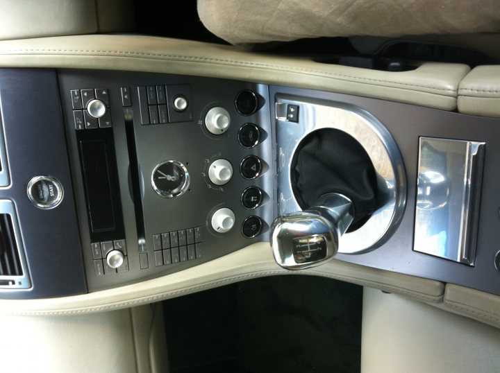 Pistonheads - The image captures the driver's side of a gray car's interior, specifically the center console area. The console provides access to various controls, including the gear shift lever. The upholstery is clean and well-maintained, with the driver's seat viewable. The stitching and texture of the leather material provide a luxurious touch to the car's design.