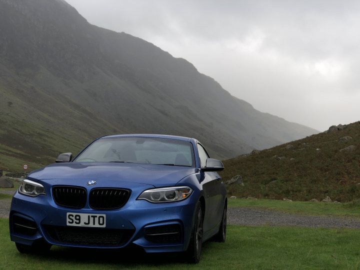 Best Quality Number Plates? - Page 3 - General Gassing - PistonHeads - In the image, a blue BMW car with a distinguishable license plate "S9 JTO" is parked on a lush, green grass field. The car is positioned at the bottom of a dramatic mountain slope, completely surrounded by miles of foggy terrain. The landscape is characterized by steep cliffs in the background, suggesting a remote area with limited human habitation. The car's sleek design contrasts with the rugged, natural environment, creating an interesting juxtaposition between man-made technology and wild nature.