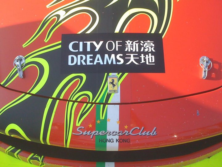 A red stop sign sitting on the side of a road - Pistonheads - The image features a red convertible car with its top down, parked outdoors and likely in the Hong Kong area. The back of the car showcases a distinctive design with yellow and green accents, possibly signifying local pride, and a small Ferrari emblem in the corner, indicating the vehicle's performance-oriented nature. The car is adorned with a black and white sticker that reads "City of Dreams" in both English and Chinese languages, suggesting a possible connection to a Chinese theme or language lesson program. The bottom of the image bears the brand name "SupercarClub" in white letters, indicating a luxury or enthusiast group might be associated with the vehicle or with the image itself.