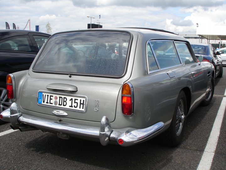 Shootingbrake Pistonheads - The image showcases a silver vintage car parked in a lot. The car sports a distinctive European license plate that reads "VIE DUR 15H". It's a two-door sedan, with the side window visible, providing a glimpse into the interior. The car is parked next to another car, indicating that the lot is occupied. The setting suggests a cloudy day, with the cloudy sky visible in the background.