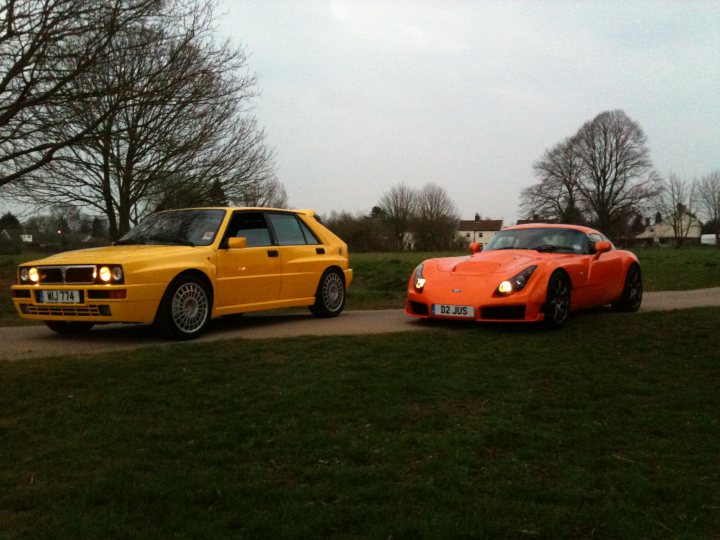 Pistonheads Seconds Endulge - The image portrays a night scene with two well-regarded sports cars: a Lamborghini and a Porsche. The Lamborghini, perhaps a Countach model, is parked on the left side of the image, its sleek lines and unique design style quickly identifiable. On the right, a Porsche, which could possibly be a 911 model, is also parked. The cars are the main focus of the image, situated in a field of green grass against the backdrop of a night sky. Interestingly, both cars are illuminated by their own headlights, casting a soft glow on the surrounding area. The contrast between the wilderness and the sophisticated vehicles suggests a sense of escape or freedom often associated with such luxury sport cars.